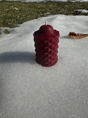 A winter photo of the scallop beeswax candle in the color red.