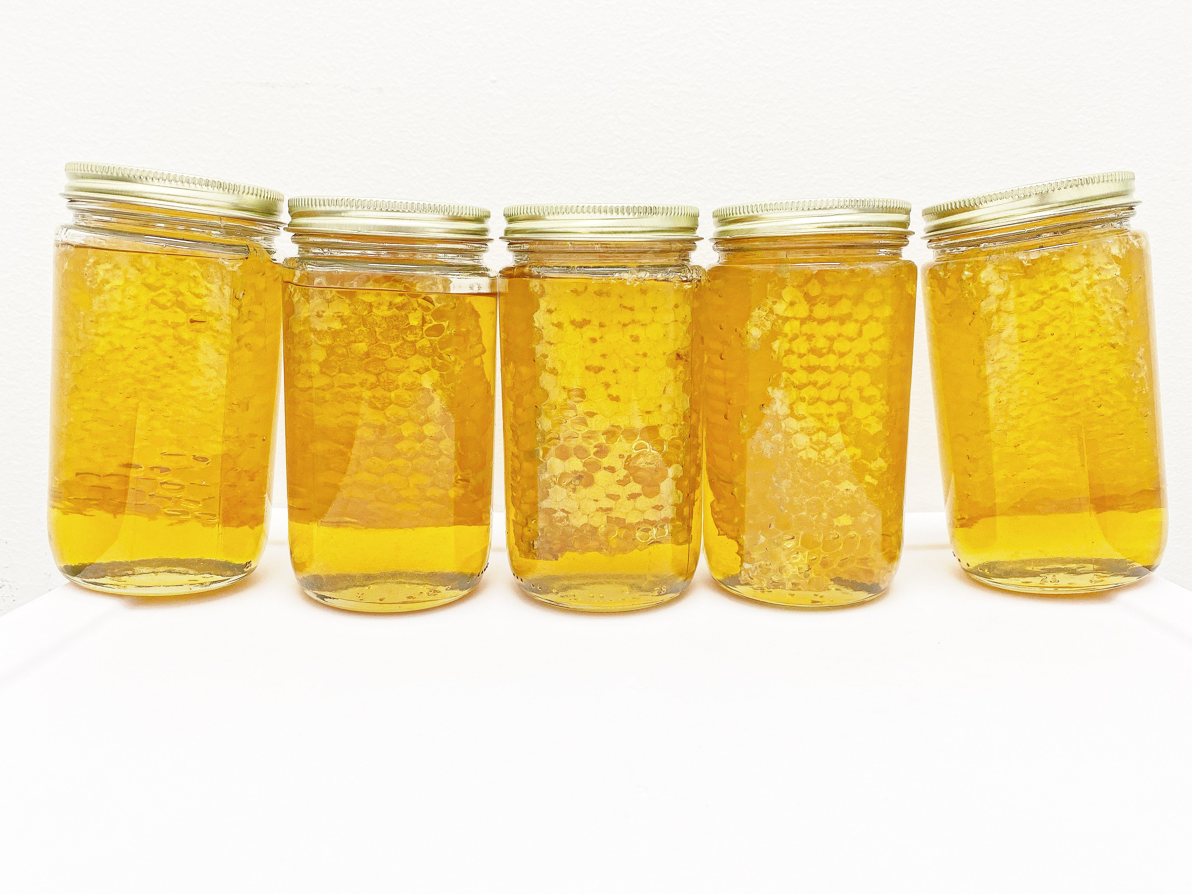 Five jars of Chunk Honey from Hardwood Honey. A mason jar with a chunk of honeycomb and filled with raw honey.