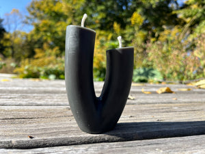 The blossom candle in the color black. Offered by Hardwood Honey.
